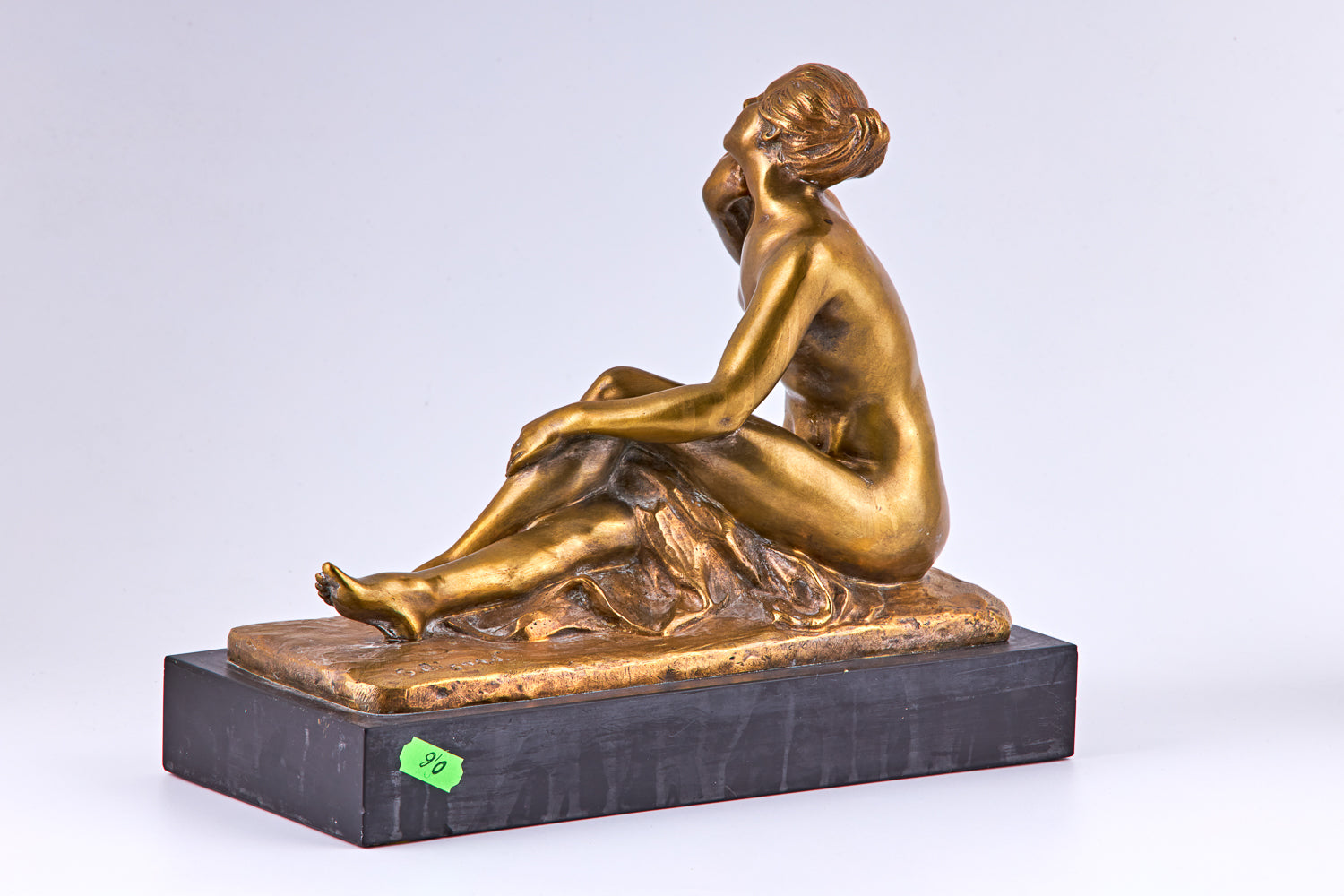 Una escultura de bronce bañada en oro de principios del siglo XX que representa a una mujer desnuda y un pájaro.