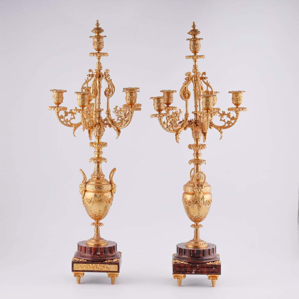 Pareja de candelabros antiguos sobre pedestal de mármol.