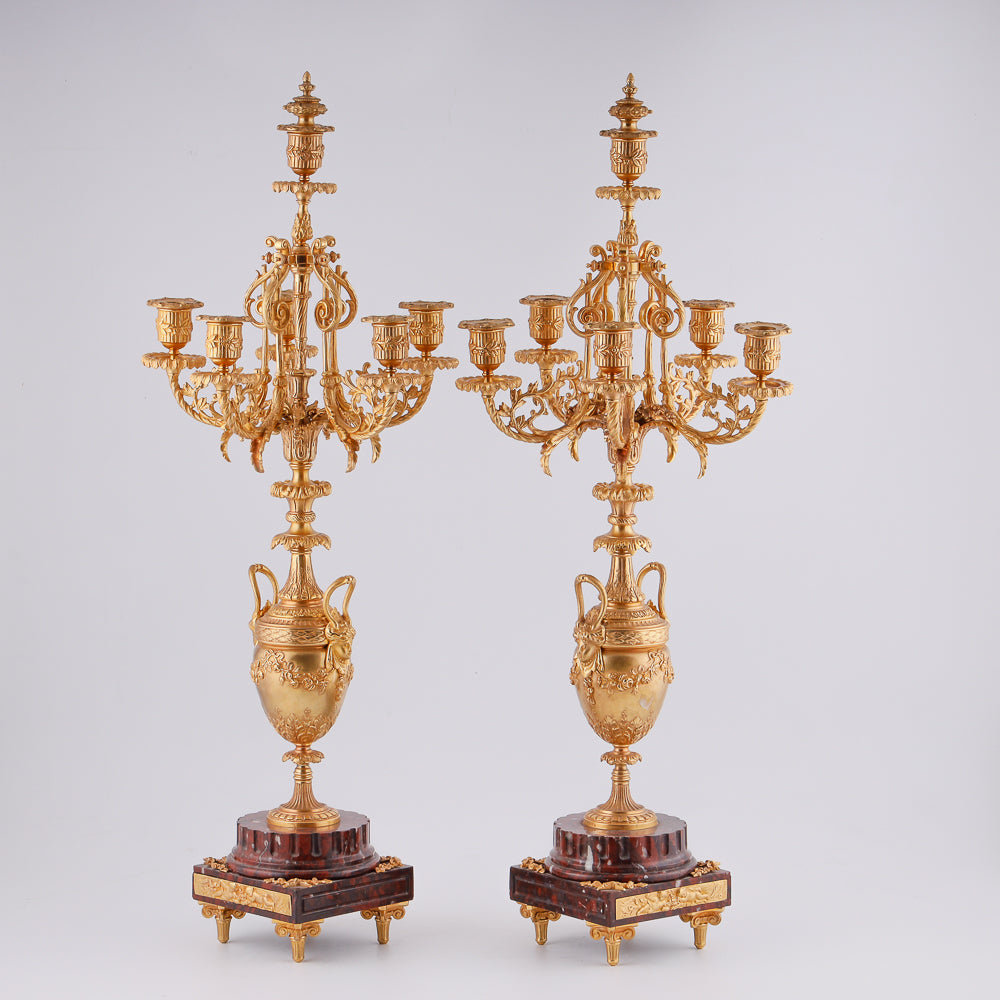 Pareja de candelabros antiguos sobre pedestal de mármol.