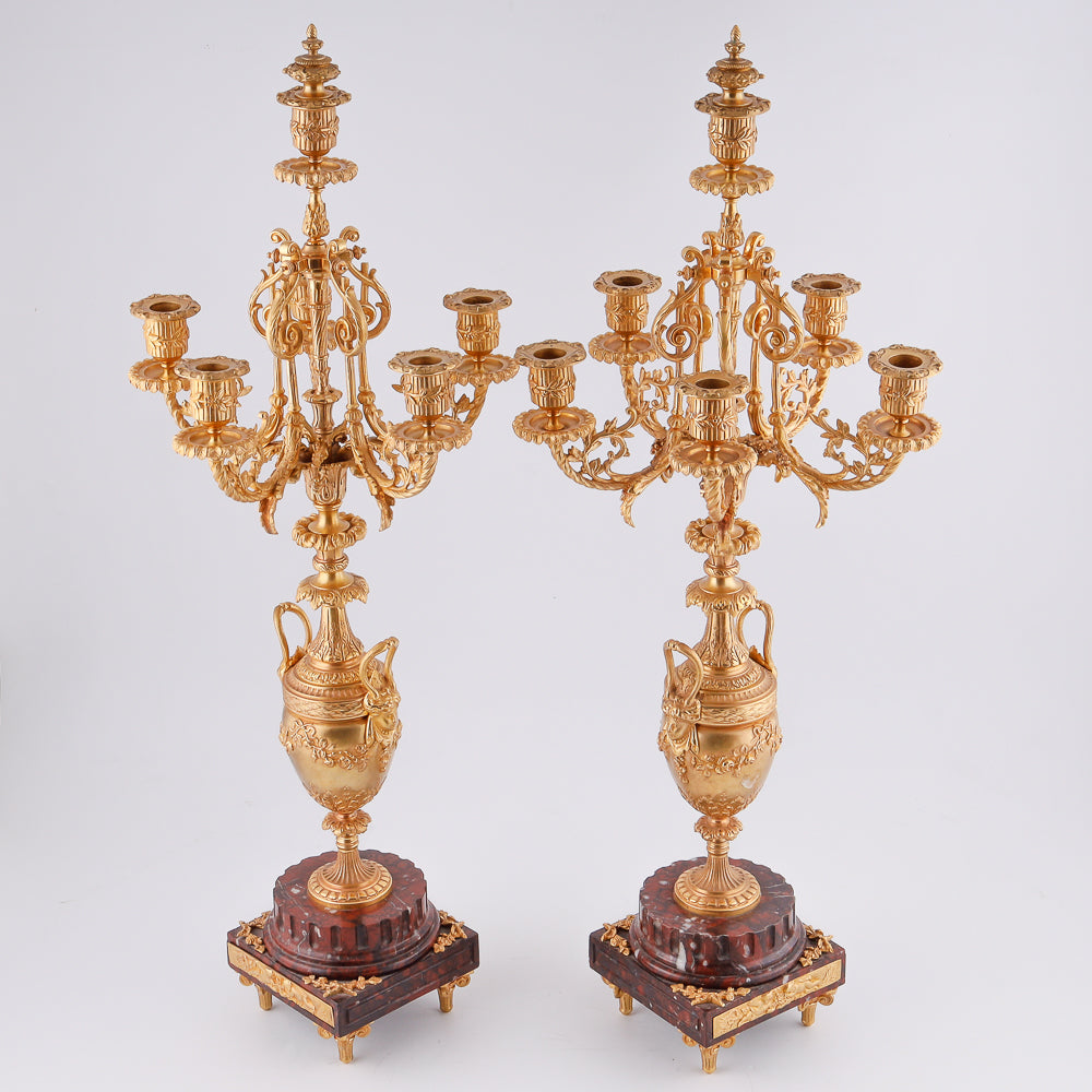 Pareja de candelabros antiguos sobre pedestal de mármol.